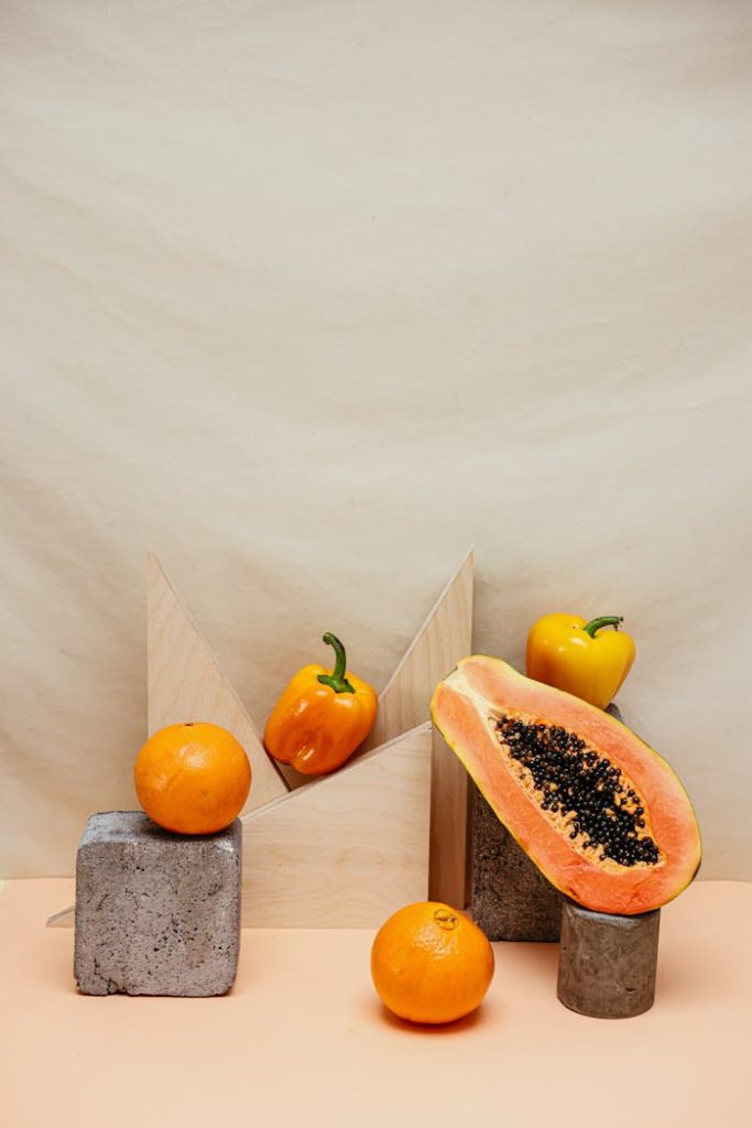 Vibrant arrangement of papaya, bell peppers, and oranges in a studio setting.